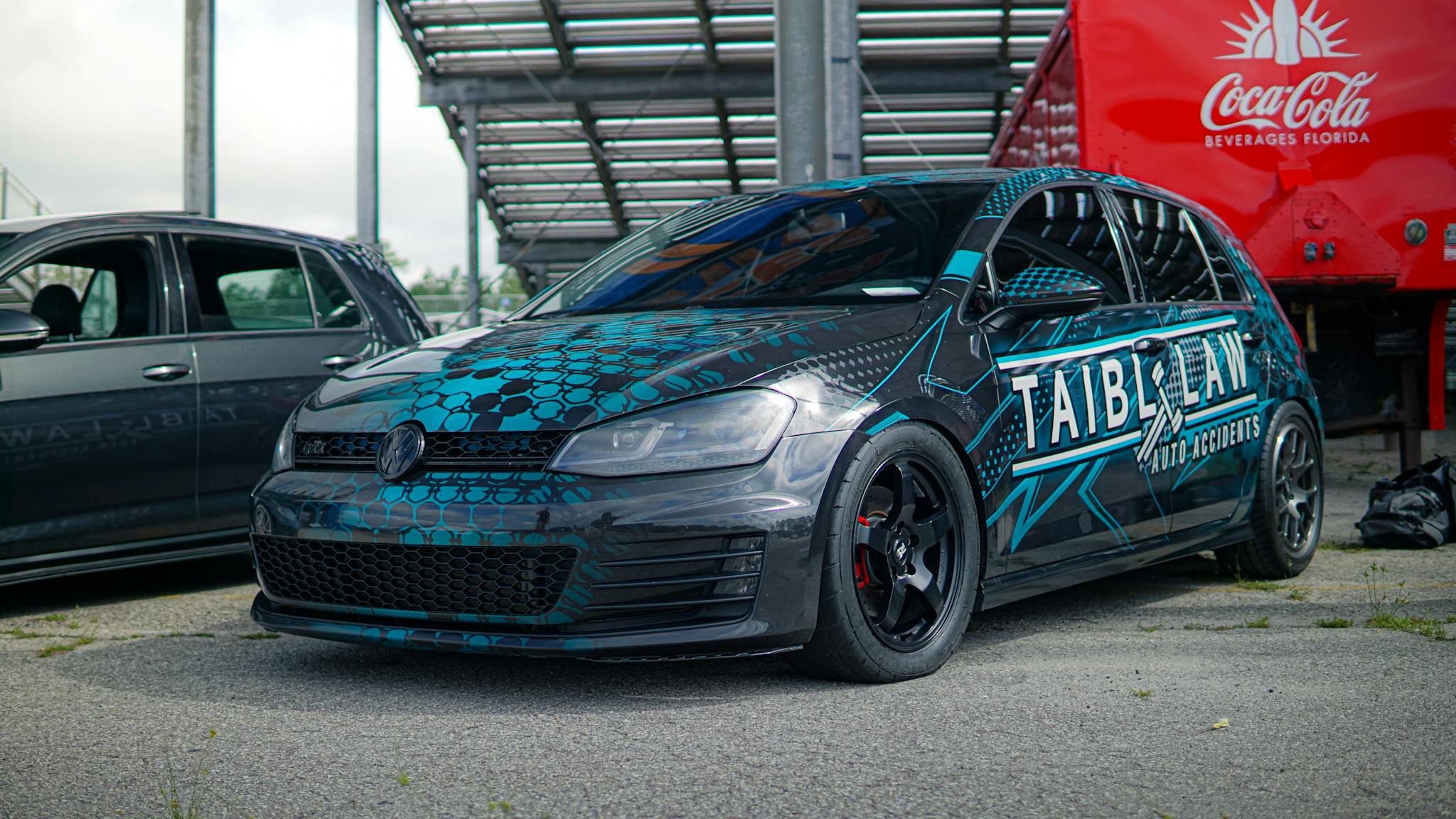 A jazzy Volkswagen Golf GTI with custom graphics parked on an urban street, featuring vibrant art and branding.